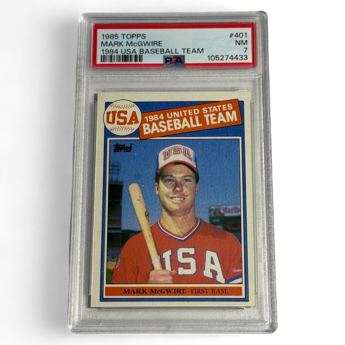 A PSA 7 near‑mint 1985 Topps #401 Mark McGwire rookie card featuring him in the 1984 USA Baseball Team uniform, an iconic Olympic‑era collectible.
