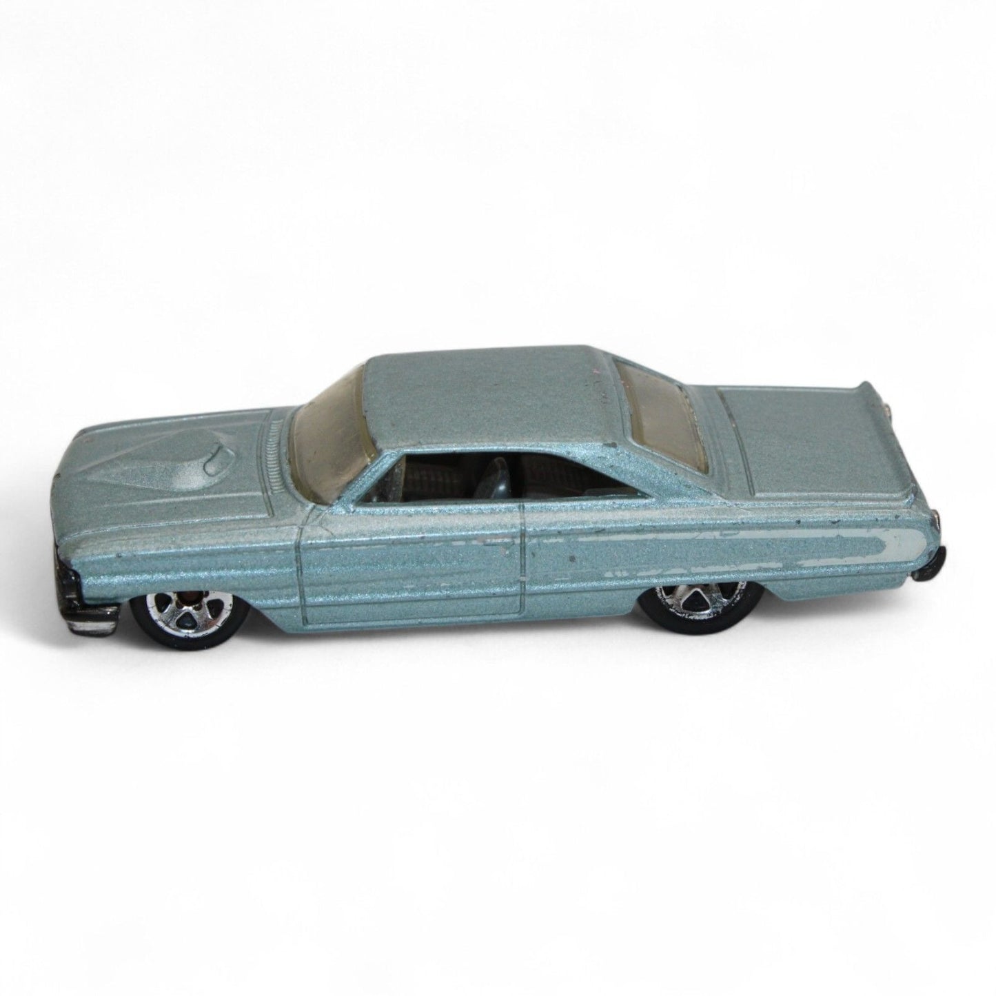 Vintage diecast model of a blue Chevy Impala, featuring chrome accents, black interior, and classic 1960s styling with minor play wear.