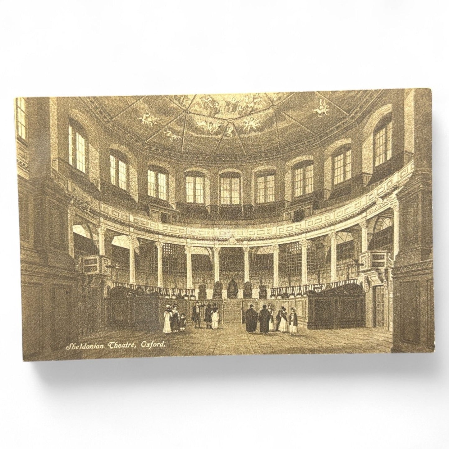 Vintage sepia postcard of the Sheldonian Theatre in Oxford, England, showing detailed interior with period figures, unused and printed in England.