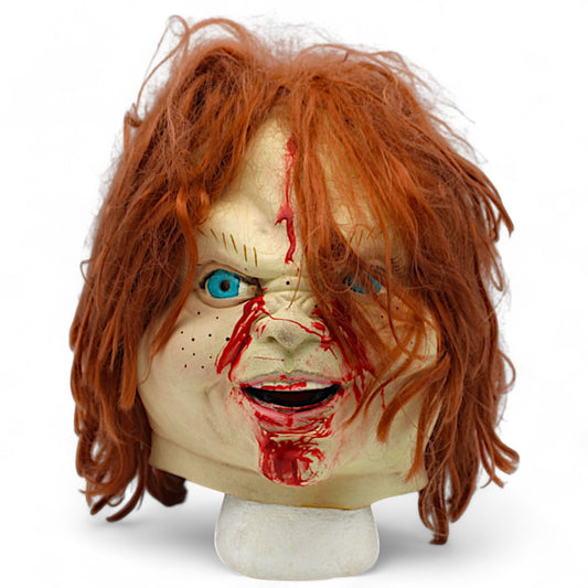 Front view of Chucky Horror Mask with bloody details, orange hair, and blue eyes.
