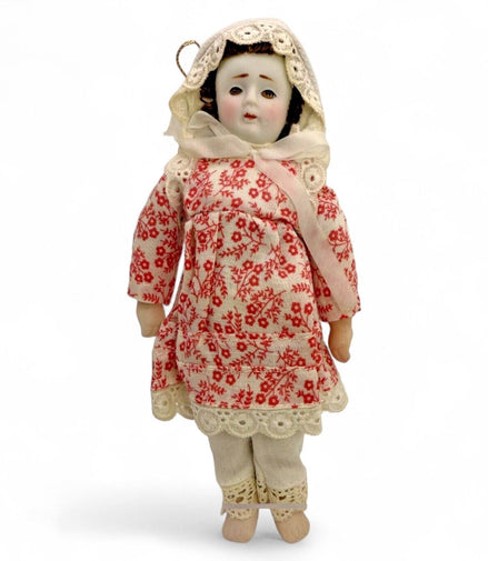 Antique porcelain doll in a floral red dress with lace trim and bonnet