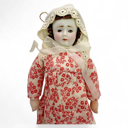 Close-up of a vintage porcelain doll in a red floral dress with lace bonnet