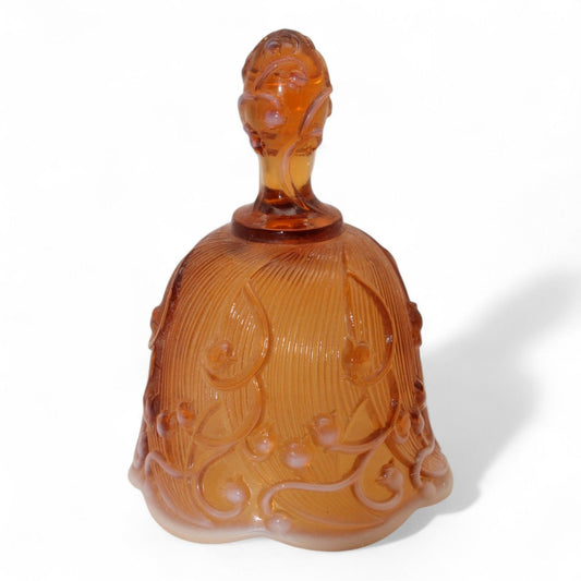 A vintage Fenton amber opalescent glass bell with embossed Lily of the Valley motif and molded handle from the 1979–1982 era, perfect for collectors.
