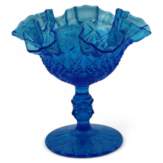 A vintage Fenton Art Glass royal blue compote with ruffled fan‑cut and block pattern on a pedestal, ideal for candy or decorative display.
