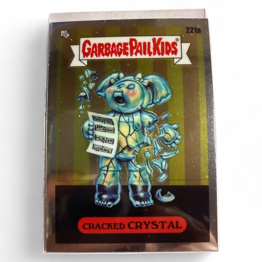 A vintage 1986 Topps Garbage Pail Kids #221a “Cracked Crystal” card showing a glass-like kid cracking apart while singing sheet music.  
