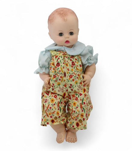Madame Alexander vintage baby doll wearing a floral romper and blue blouse