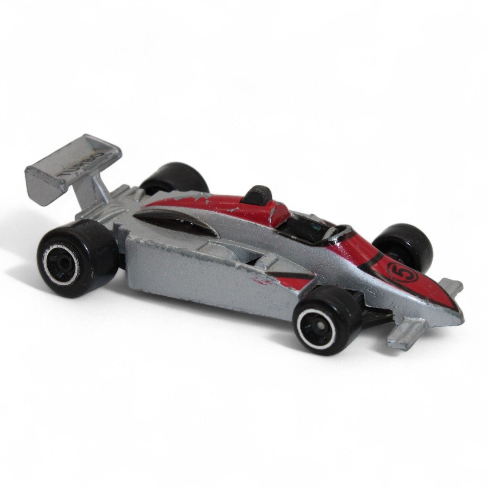 A silver and red diecast formula‑style race car toy with number 5 livery, vintage 1:64 scale metal model in fair play condition.
