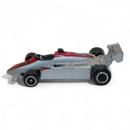 A silver and red diecast formula‑style race car toy with number 5 livery, vintage 1:64 scale metal model in fair play condition.
