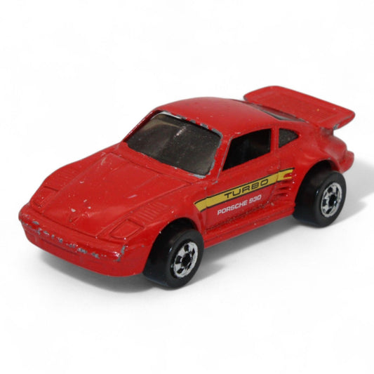 This vintage red Porsche 930 Turbo diecast toy car features black wheels, side decals, and classic styling, ideal for collectors or display.
