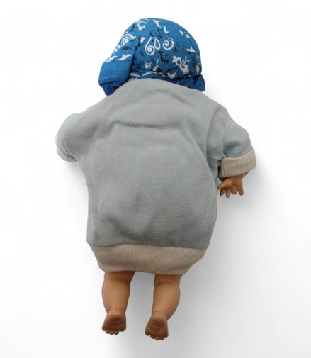 Back view of vintage baby doll with blue scarf